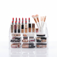 Clear acrylic makeup organizer box with multiple compartments filled with cosmetics and beauty products
